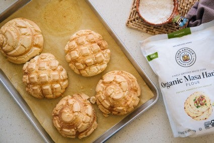 Sheet pan of Conchas de Maíz next to bag of masa harina